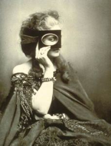 Woman in 19th century photograph holding a card with an oval up to her eye. Her shoulders are bare, and her robe looks rich and soft.