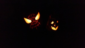 Two jack o'lanterns at night (Spiderman, and a goofy one-toothed traditional pumpkin)